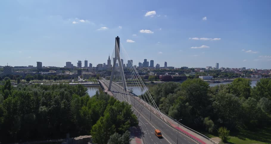 Vehicles travel a bridge over a river to and from a large city