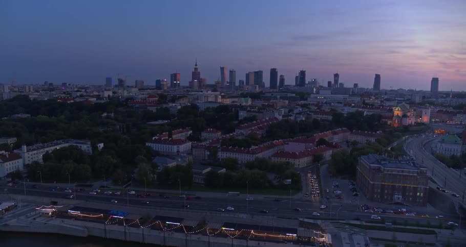 Cars travel on highways and city streets with skyscrapers on the horizon at sunset