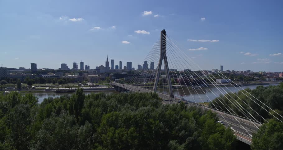 A suspension bridge leading over a river into a city