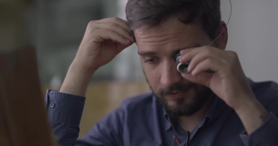 A man adjusting a loupe on his eye before examining a device in a box
