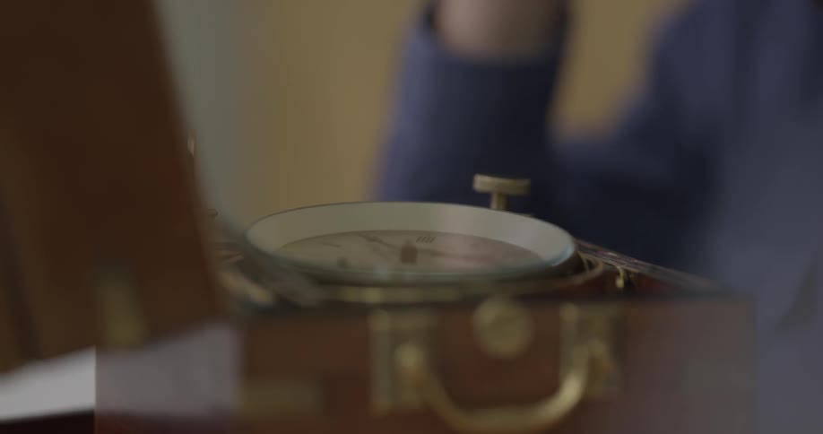 A man wearing a loupe using a screwdriver on a mechanical box