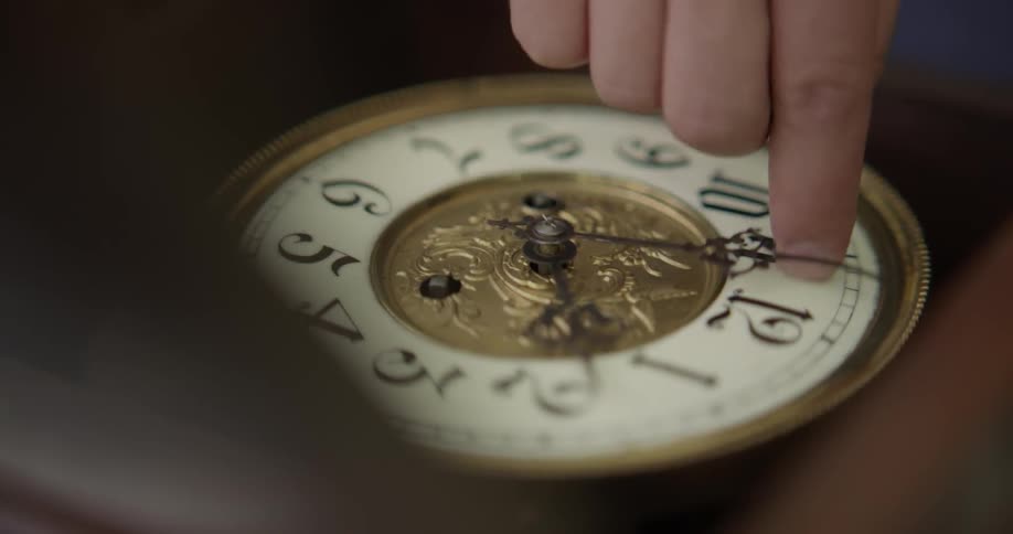 A man turns the hands on a clock
