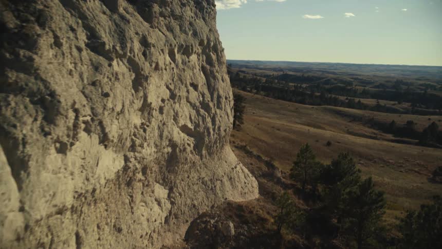 A mountain cliffside lined with trees sits motionless