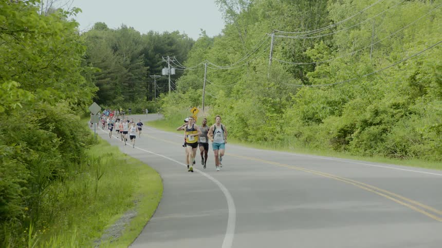 A group of runners run on the windy road together