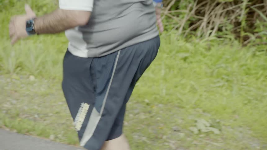 A man is jogging and checking his watch