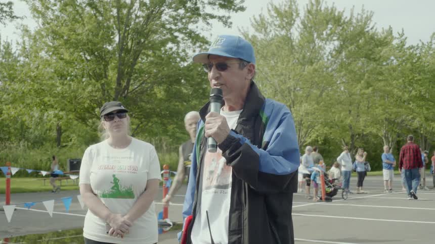 A man at a running race speaks in to a microphone