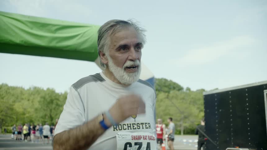 An elderly man runs across the finish line of a race