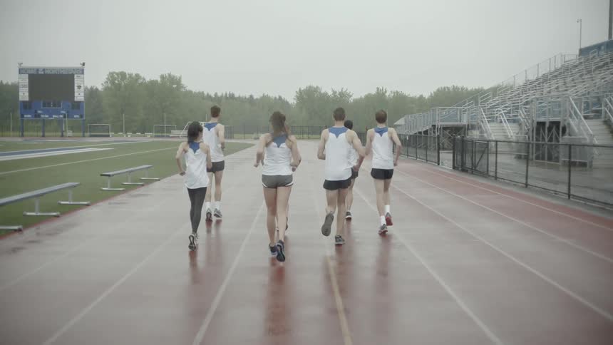 A group of teenagers jog along a stadium track