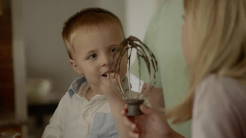 Two young children lick off batter from a mixer beater