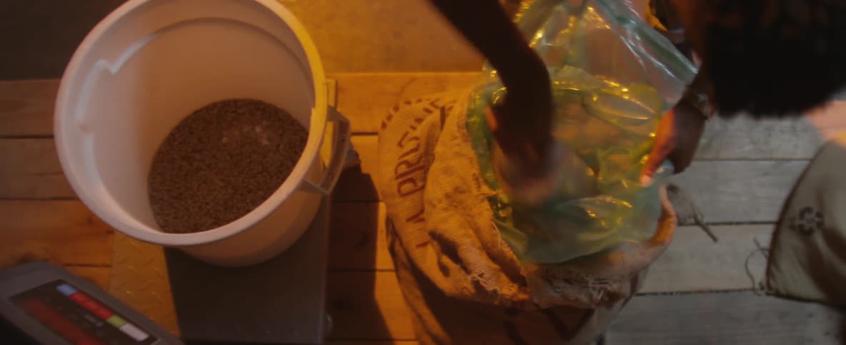 A person is digging scoops from a bag and dumping them in a bucket
