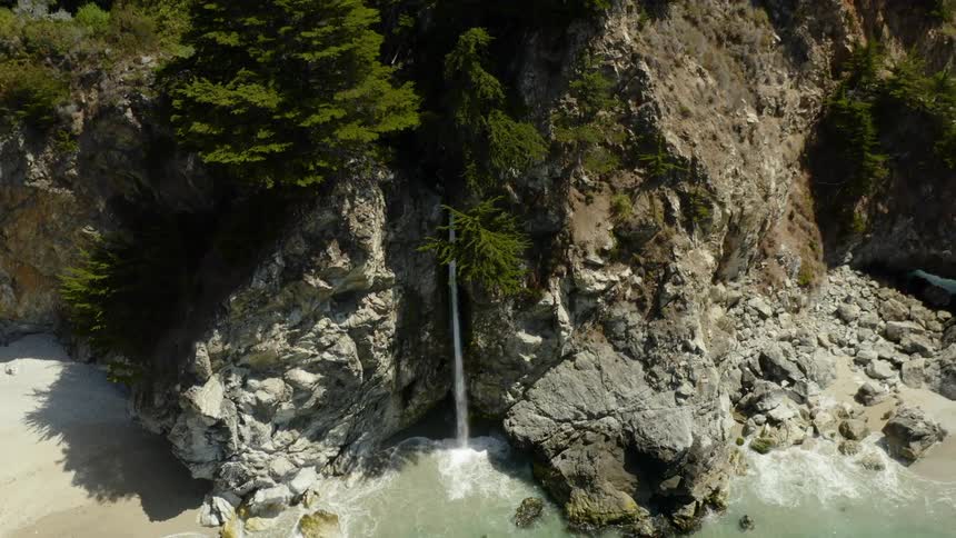 The waterfall falls off the cliff into the shore