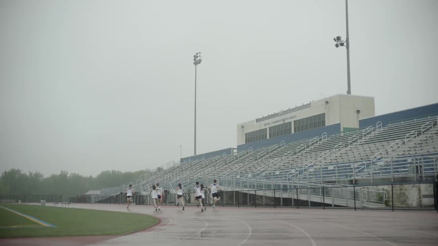 Athletes run on running track on a cloudy day