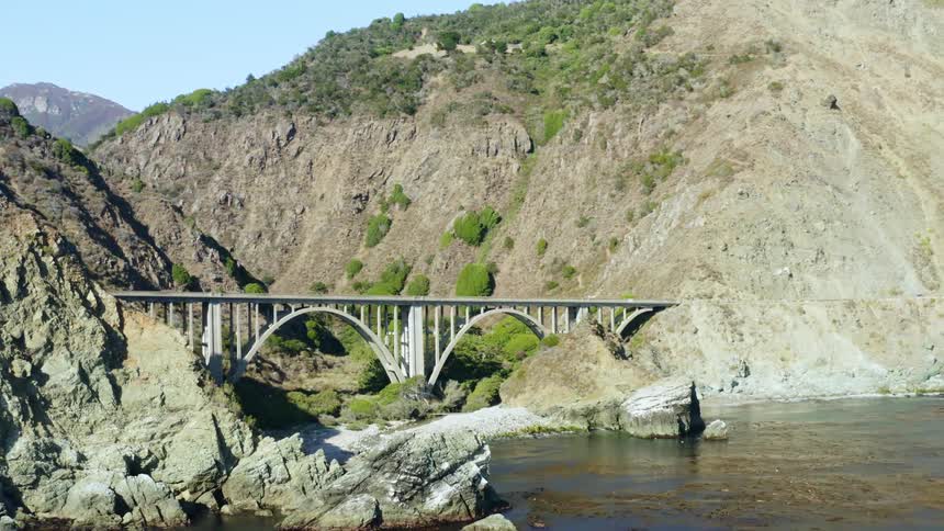 Landscape view of a bridge in between large hills