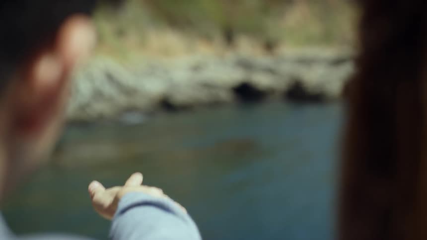 A man and woman standing together looking out over a river