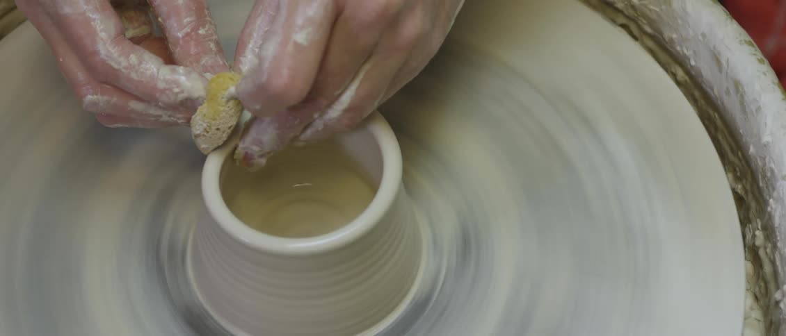 Woman sculpting a vase on a spinning pottery wheel