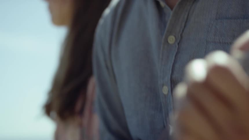 Male playing a ukulele while sitting next to a female outdoors