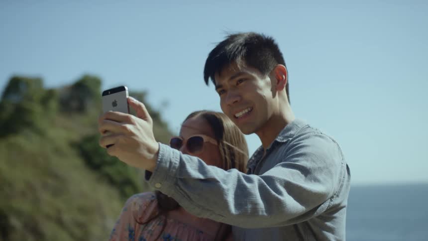 A couple poses for a selfie while standing outdoors