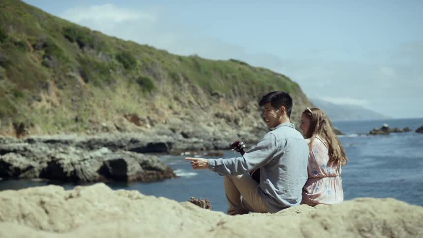 Two people sit next to the ocean