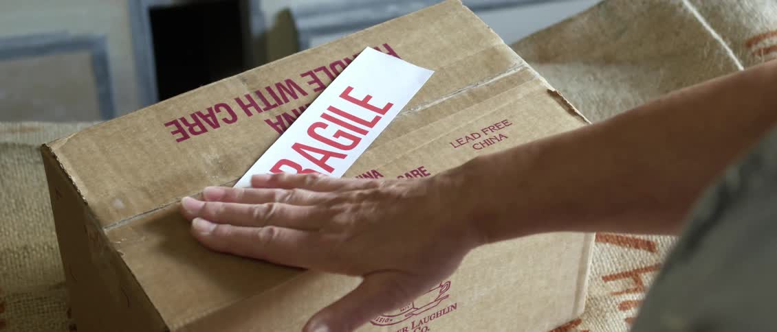 A person places a 'fragile' sticker on a box