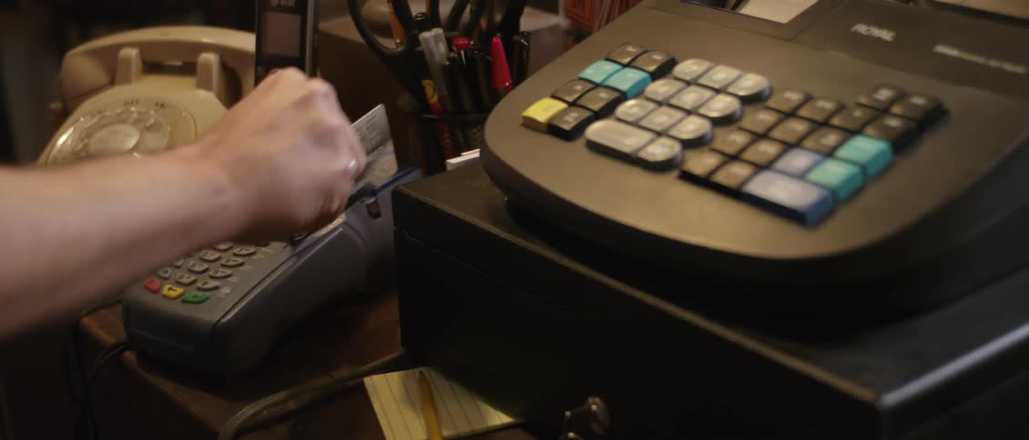Person uses adding machine then slides credit card through equipment