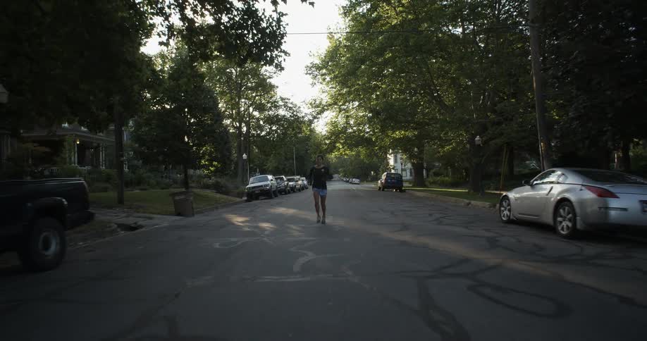 A person is running down a street as the sun rises