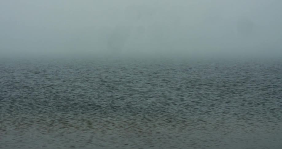 Waves flow on open water on a foggy morning