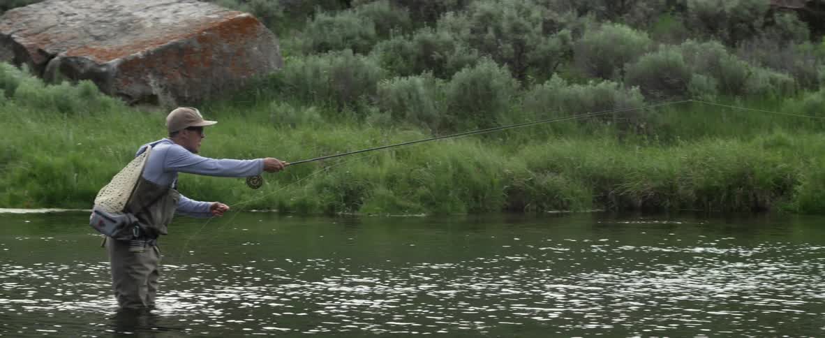 Man stands in a river fly fishing