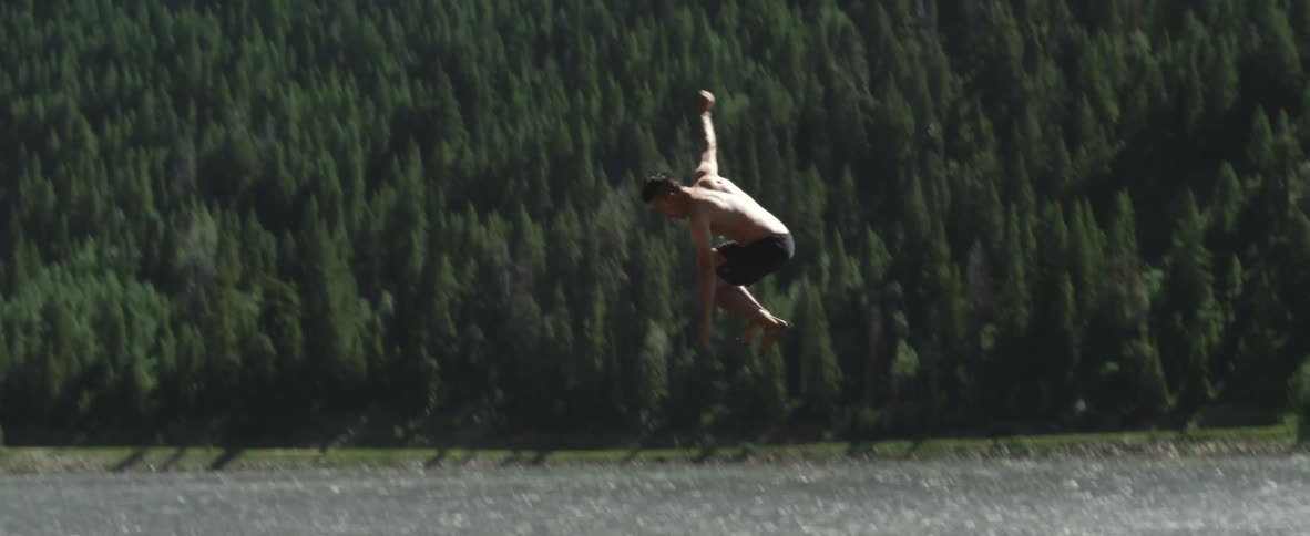 A man is swinging on a rope then falling in the water below