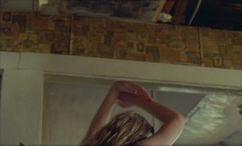 Blonde woman wearing headphones dances indoors during daylight