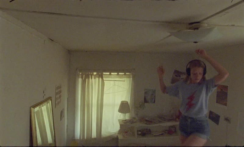 A teenager jumps on her bed while listening to headphones
