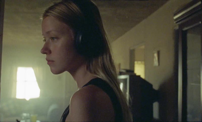 A young girls with headphones on walks in to a room