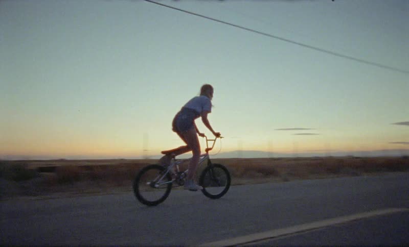 A woman rides her bicycle fast down the road