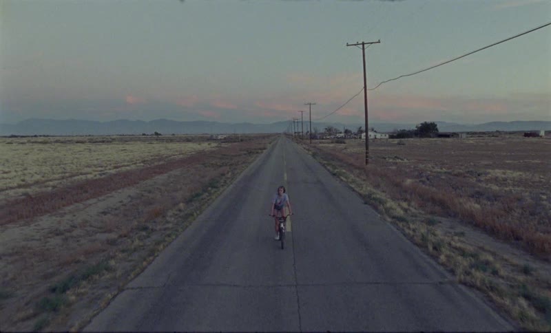 Young woman rides on a bicycle on the road at dusk
