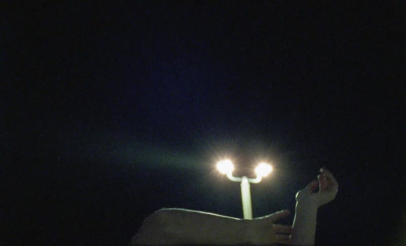 A young girl dances with her arms above her head at night