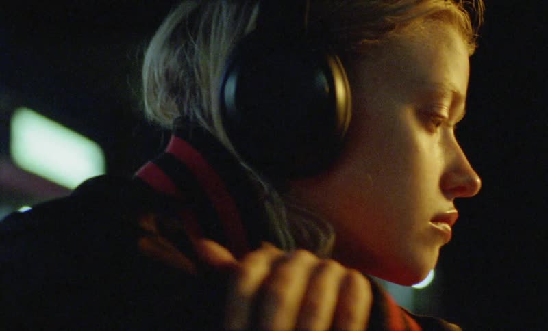 A woman wearing headphones rests her head on her arms