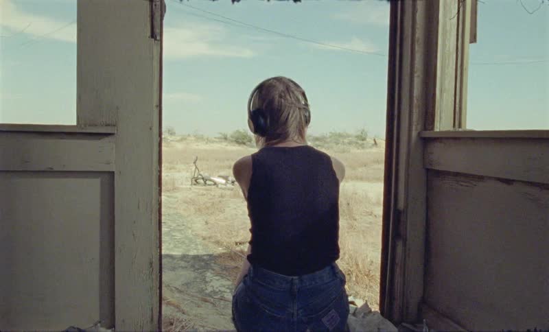 A young girl sits in a doorway looking outside