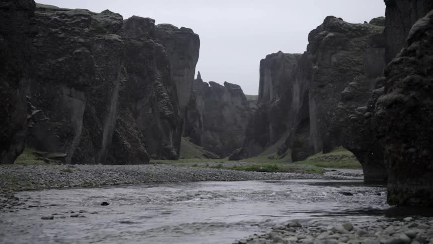 A small stream sits between some large rocks on a cloudy day