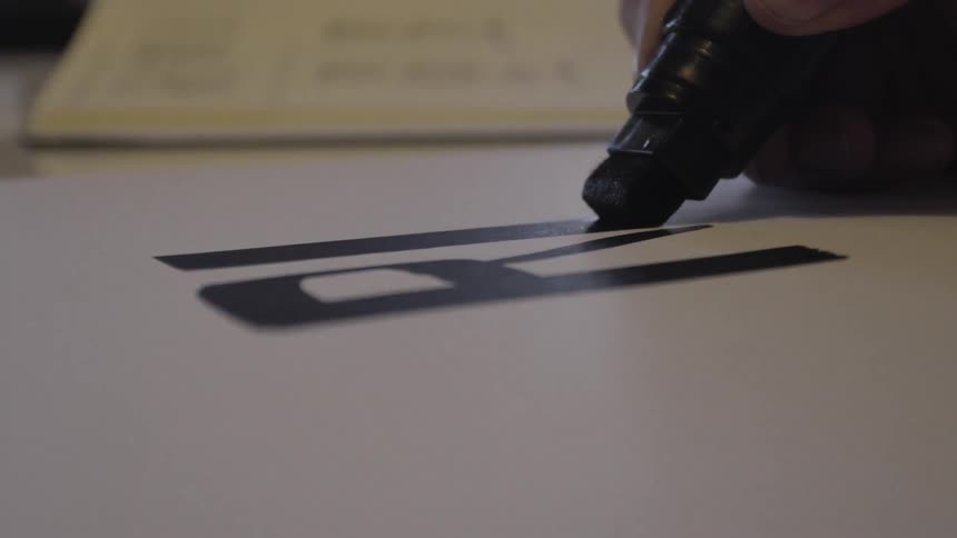 A person is writing letters with a marker on paper