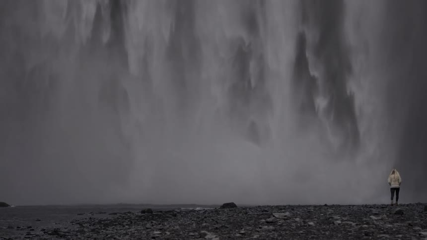 Person taking a walk next to a waterfall