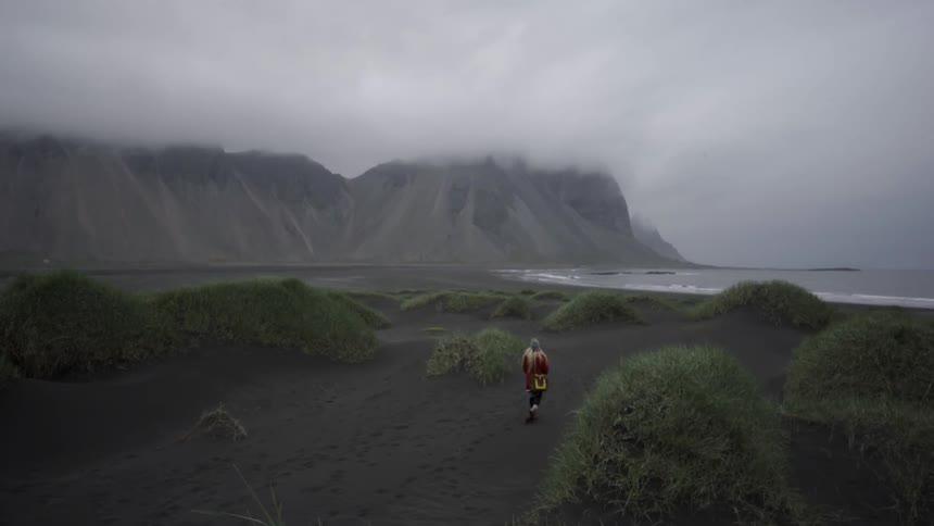 A person is walking towards the water on a foggy day