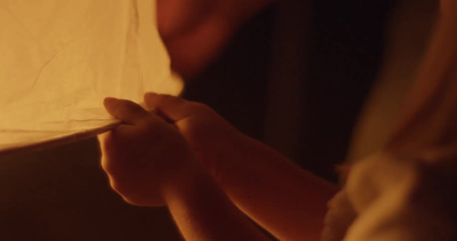 Girl holding the edge of a chinese lantern at night