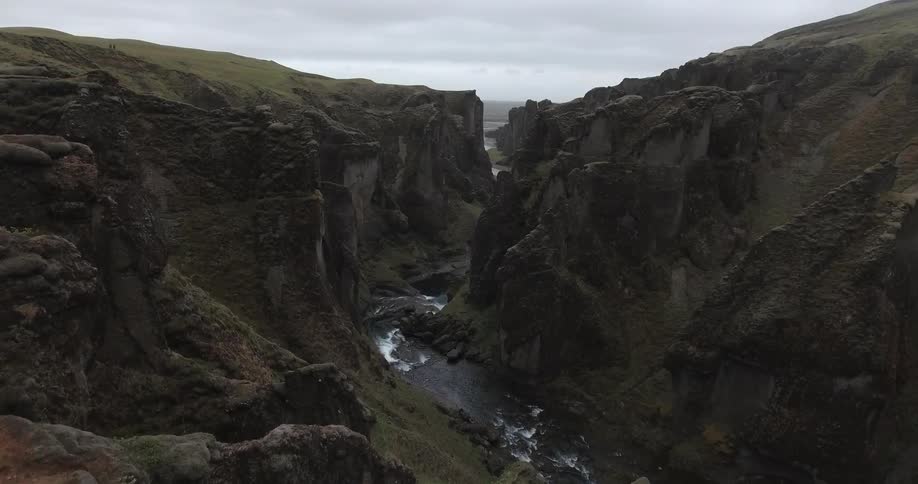 A hiker stands at a mountain peak overlooking a stream