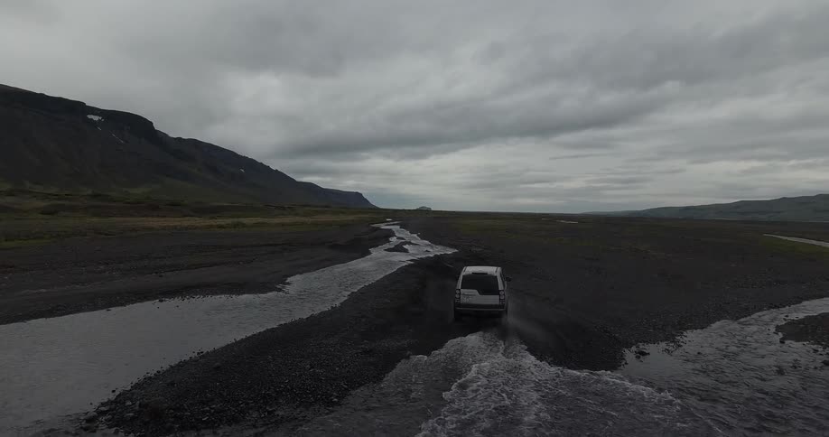 An suv drives through a river bed