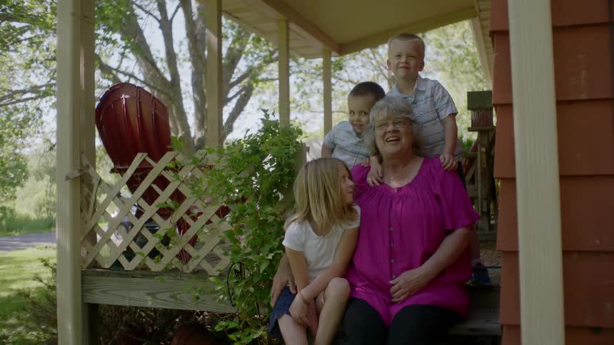 Grandmother and her grandchildren cluster together on the front porch