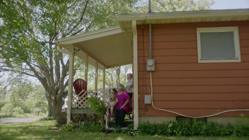 A family sit on the porch together on a windy day