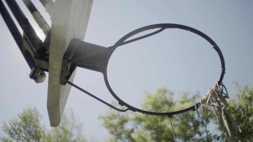 Worms eye view of a ball going through a battered basketball hoop