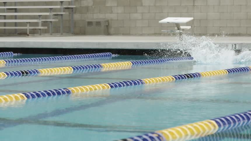 A man dives off a starting block in to a pool