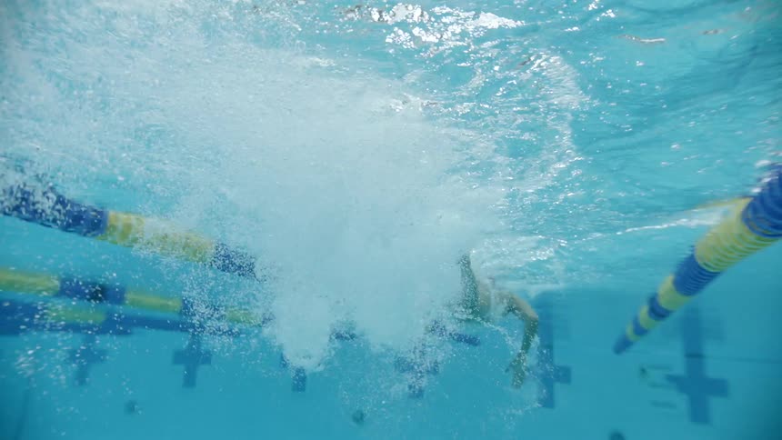 From underwater in a large pool a man can be seen swimming across very quickly