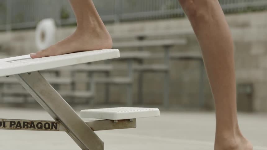 A person climbs the steps to the diving board near the pool