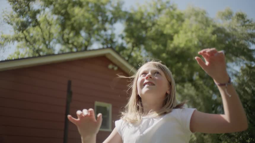 Little girl plays ball in the garden during daylight